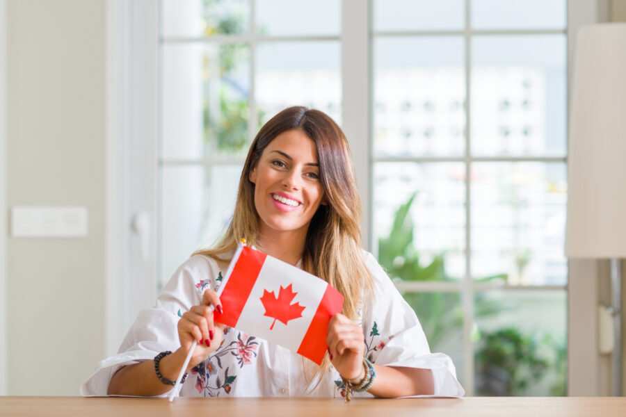 Smiling woman holding a small Canadian flag, representing Canadian identity and dental care options in the context of the Canadian Dental Care Plan (CDCP).