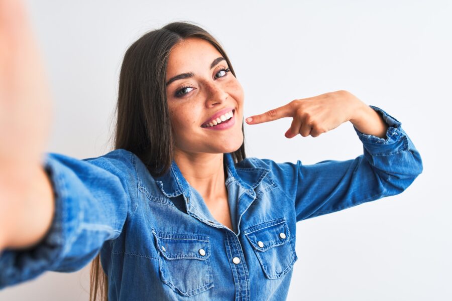 Woman with a great smile pointing proudly to her teeth.