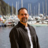 Zahir Nathoo standing outdoors near a marina, representing dental tourism insights and Canadian dental care options.