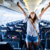 Woman celebrating on an airplane, representing the excitement of dental tourism for Canadians traveling to Turkey for affordable dental care.