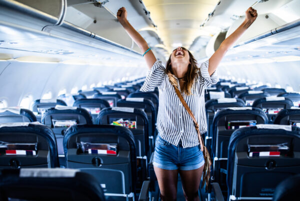Dental Pathways - Joyful woman standing in a plane and celebrating its safe landing.