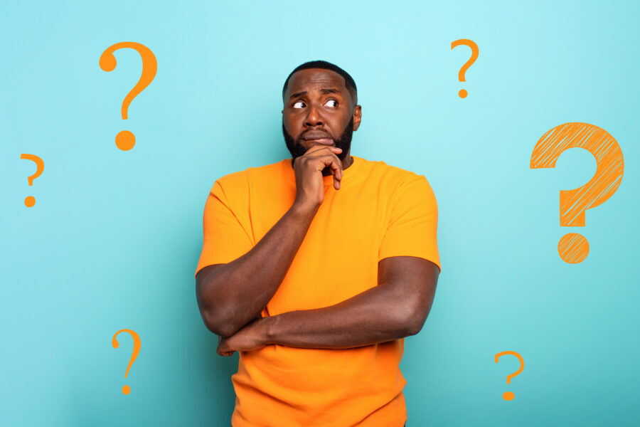 Man in orange shirt looking confused with question marks, representing uncertainty about dental treatment options in Turkey.