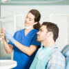 Dentist showing treatment plan to patient in dental clinic, emphasizing affordable dental care options for Canadians considering dental tourism.