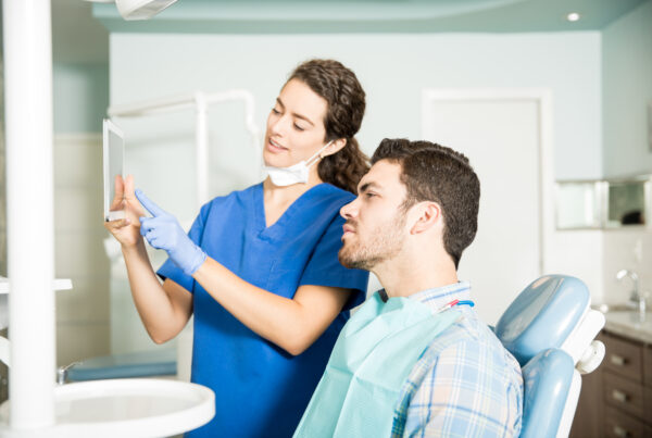Dentist showing digital treatment plan to patient during dental consultation.