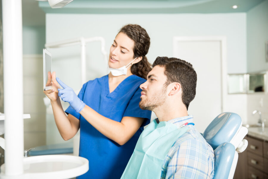 Dentist showing digital treatment plan to patient during dental consultation.